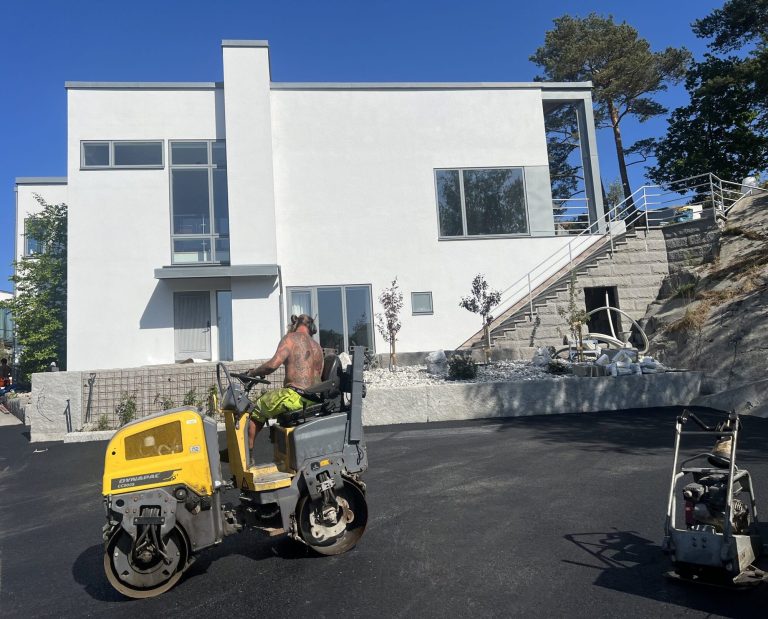 Asfalterad garageuppfart framför vit villa