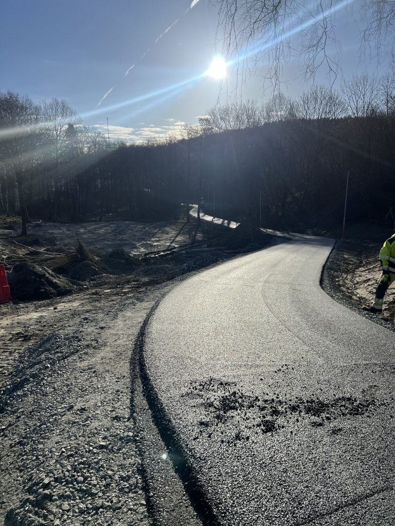 Mörk nylagd asfaltväg i mjuk kurva