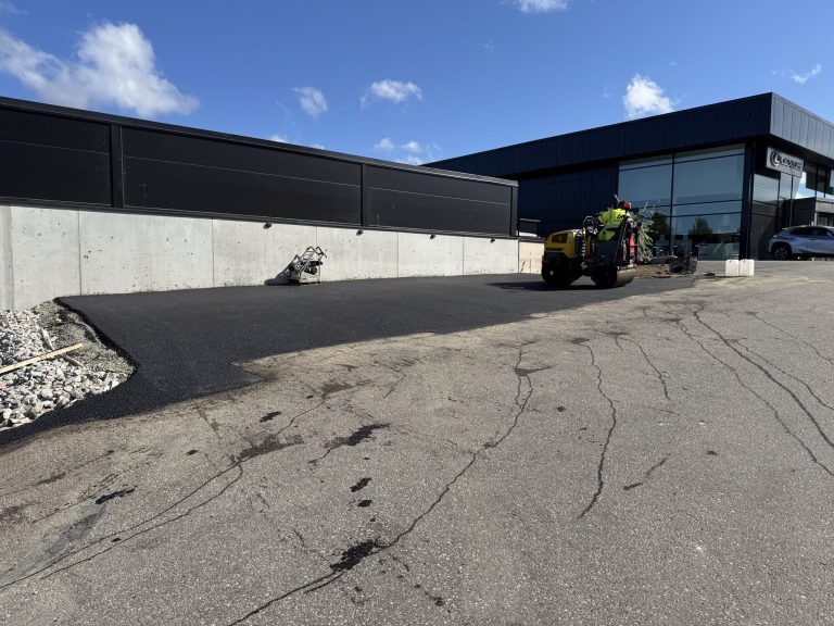 Asfalterad parkeringsyta vid företagsbyggnad