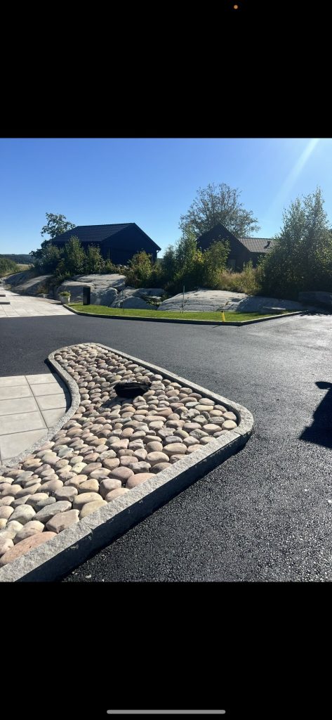 Asfalterad uppfart med kant av marksten och storgatsten